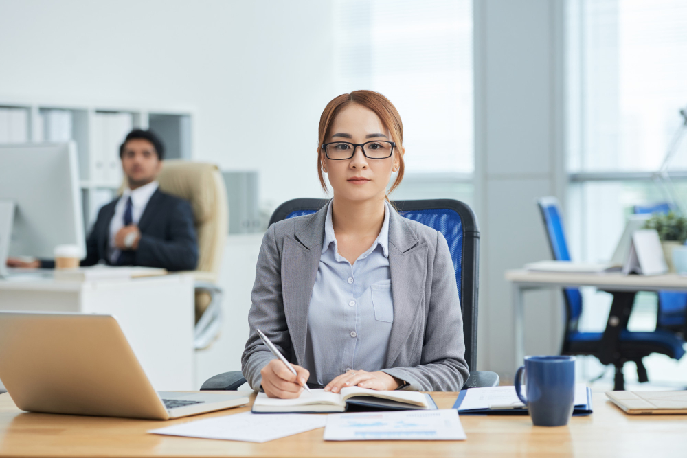 Accounting Staff sedang mencatat transaksi keuangan di kantor.